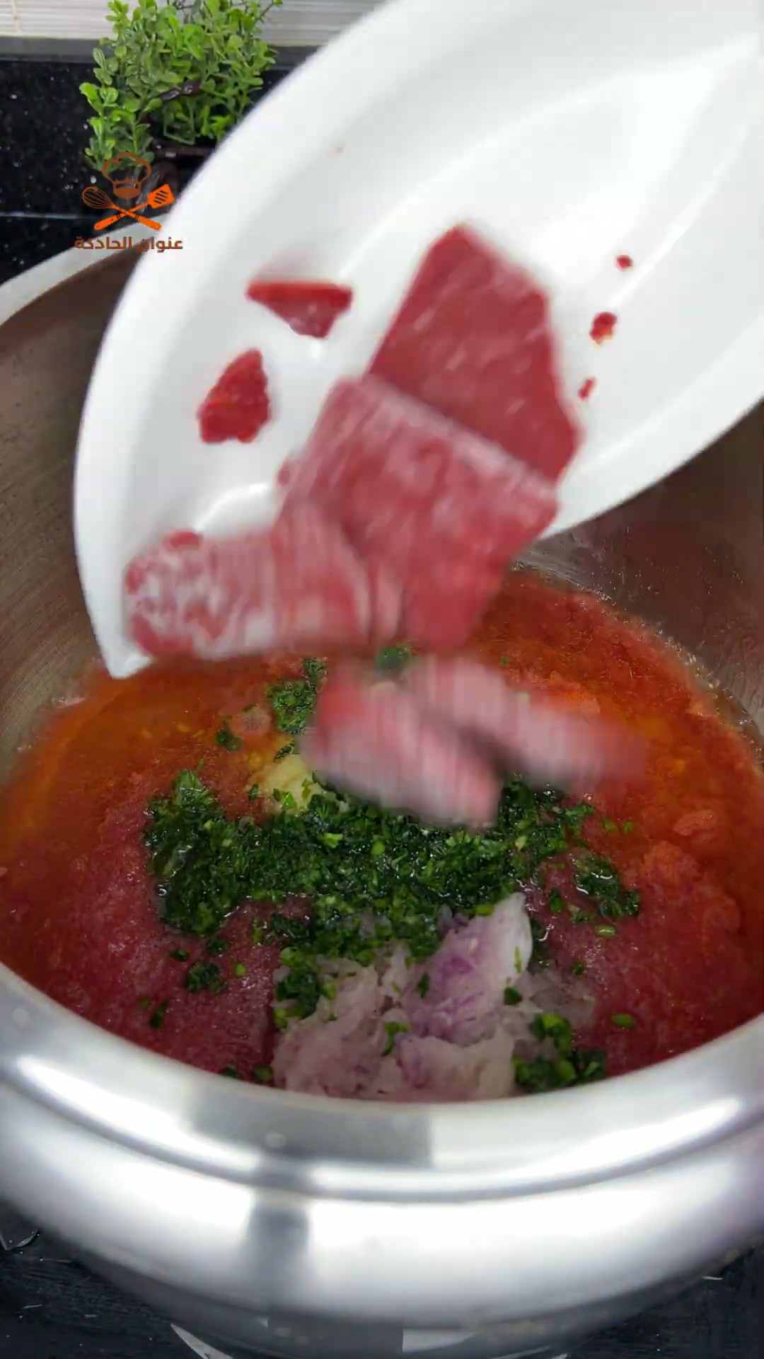 Adding ground beef to grated tomato, chopped herbs and sliced red onion
