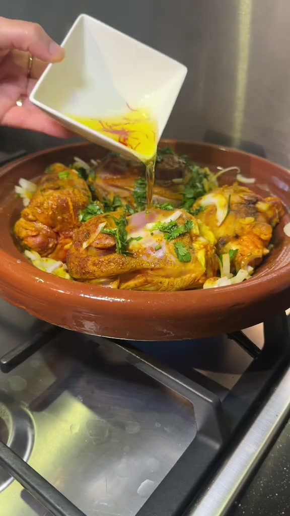 Pouring saffron water over the lamb before covering the tagine
