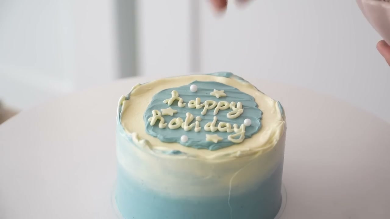 Blue ombre bento cake with white top, happy holiday lettering and buttercream dots