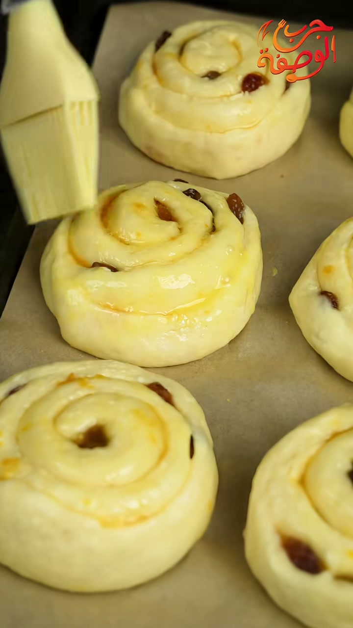 Brushing the risen raisin swirls with egg and milk wash