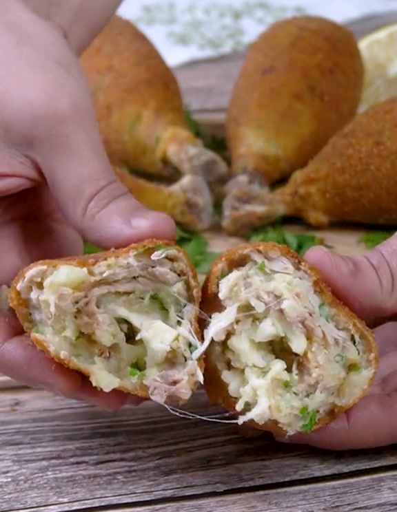 A chicken drumstick croquette broken open, showing the shredded chicken, potato and melted mozzarella filling