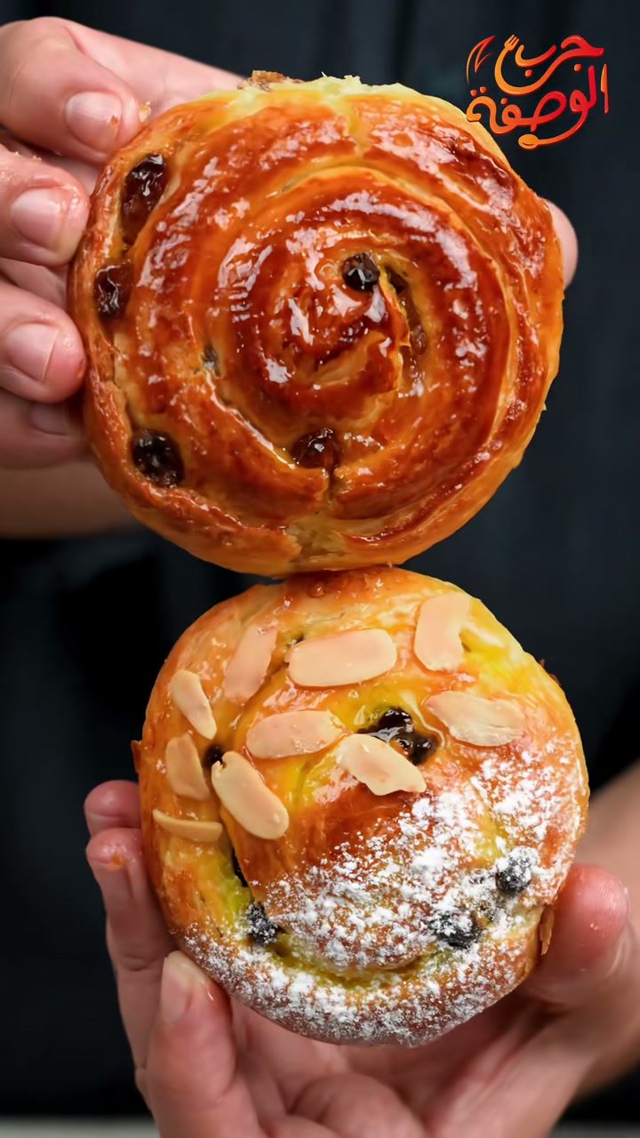 Two chnek: a raisin swirl and a chocolate chip swirl topped with sliced almonds and powdered sugar