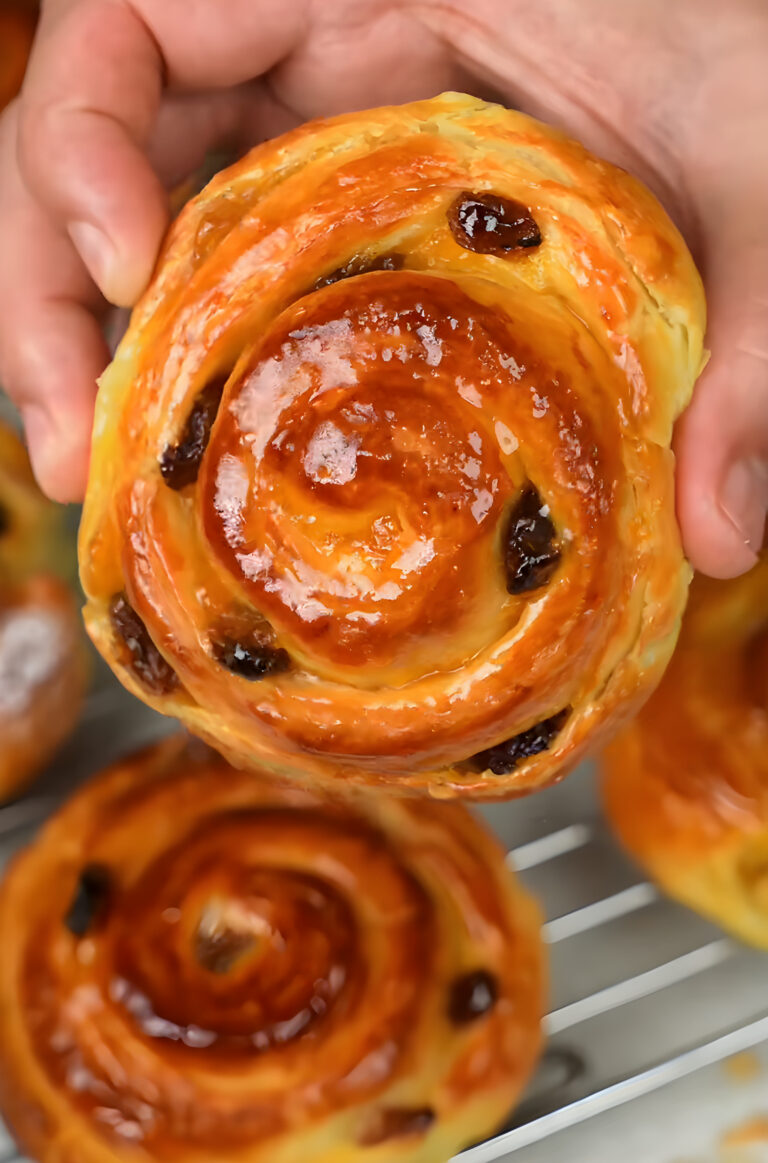 Moroccan chnek: a glossy laminated brioche swirl with raisins held in two hands