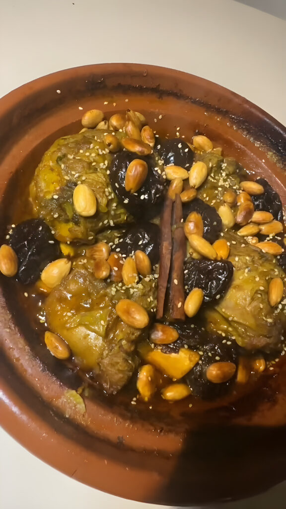 Moroccan lamb tagine with prunes, topped with caramelized prunes, fried almonds, sesame seeds and a cinnamon stick