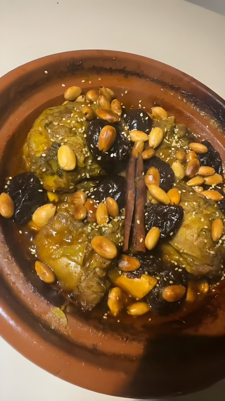 Moroccan lamb tagine with prunes, topped with caramelized prunes, fried almonds, sesame seeds and a cinnamon stick