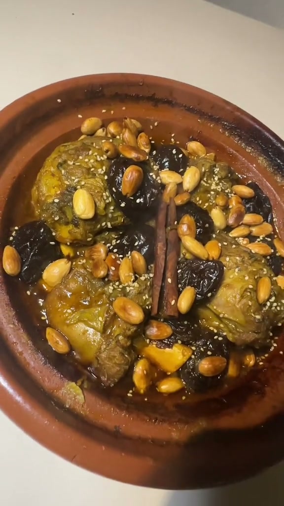 Moroccan lamb tagine with prunes, topped with caramelized prunes, fried almonds, sesame seeds and a cinnamon stick