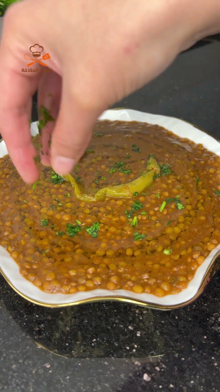 Moroccan lentils (l'3des) in a white serving bowl, topped with a green chili pepper and chopped parsley