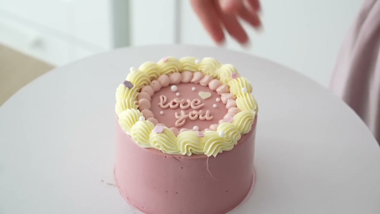 Pink bento cake with a pale shell border and love you written in buttercream