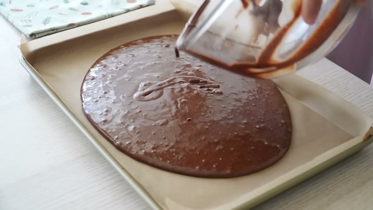 Pouring chocolate cake batter into a parchment-lined sheet pan