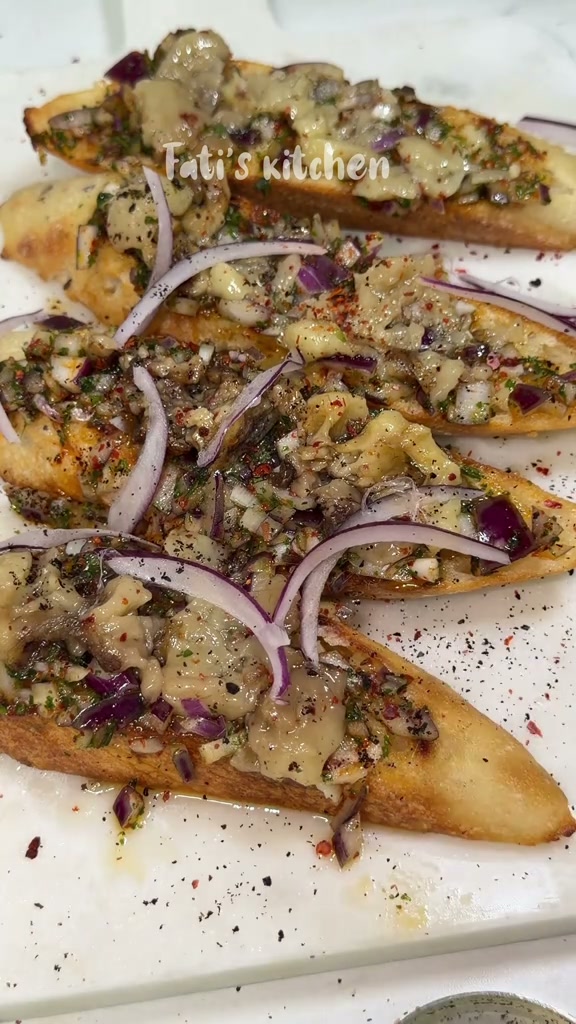 Roasted bone marrow toasts topped with red onion relish and sliced red onion