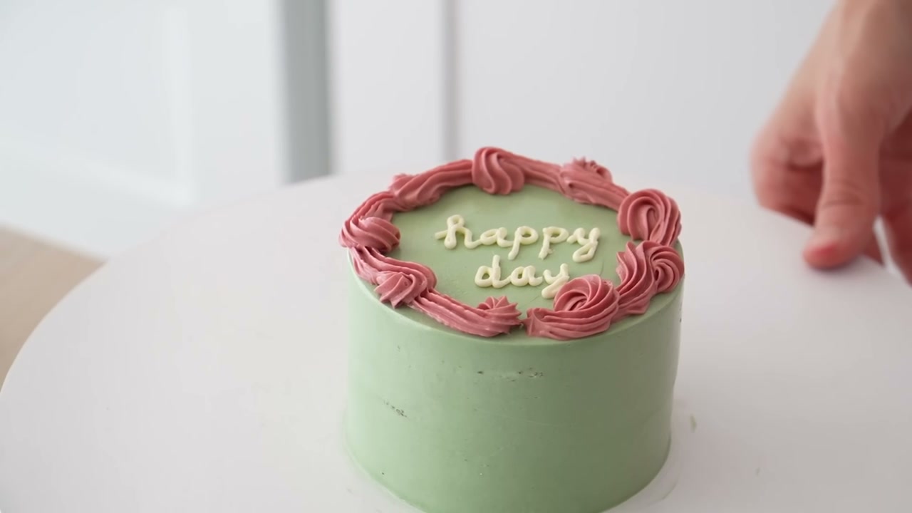 Sage green bento cake with a pink piped border and happy day lettering
