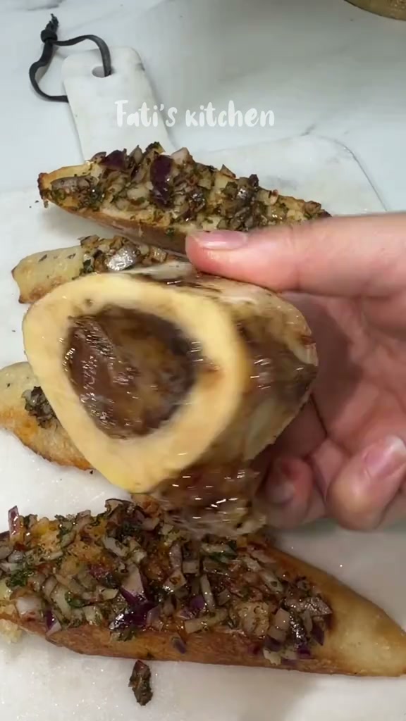 Scooping roasted marrow out of the bone onto the toasts