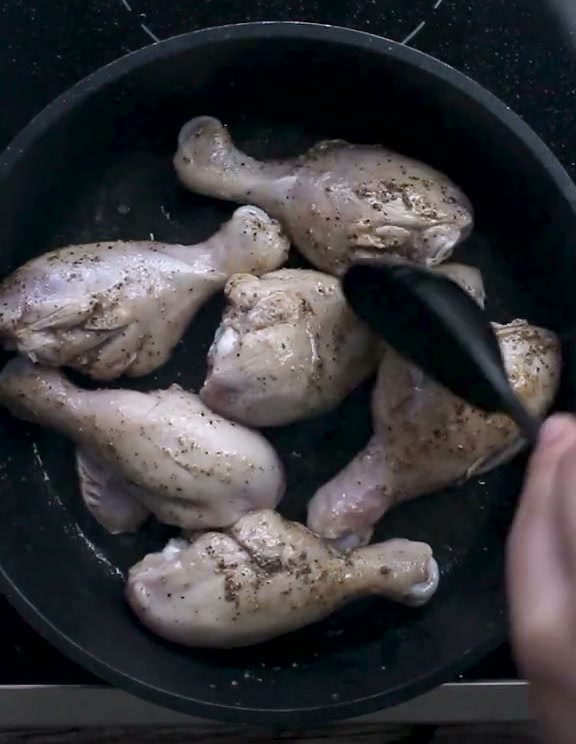 Seasoned chicken drumsticks browning in a pan