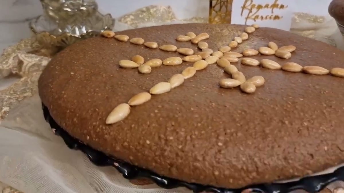 A large round of sellou decorated with almonds on a Ramadan table, with a Ramadan Kareem card behind