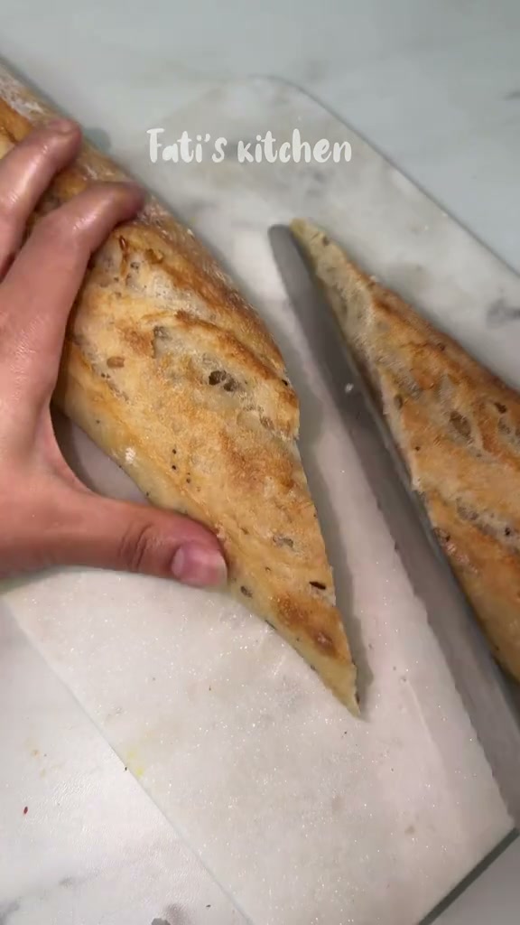 Slicing a baguette lengthwise on a long diagonal for toasts