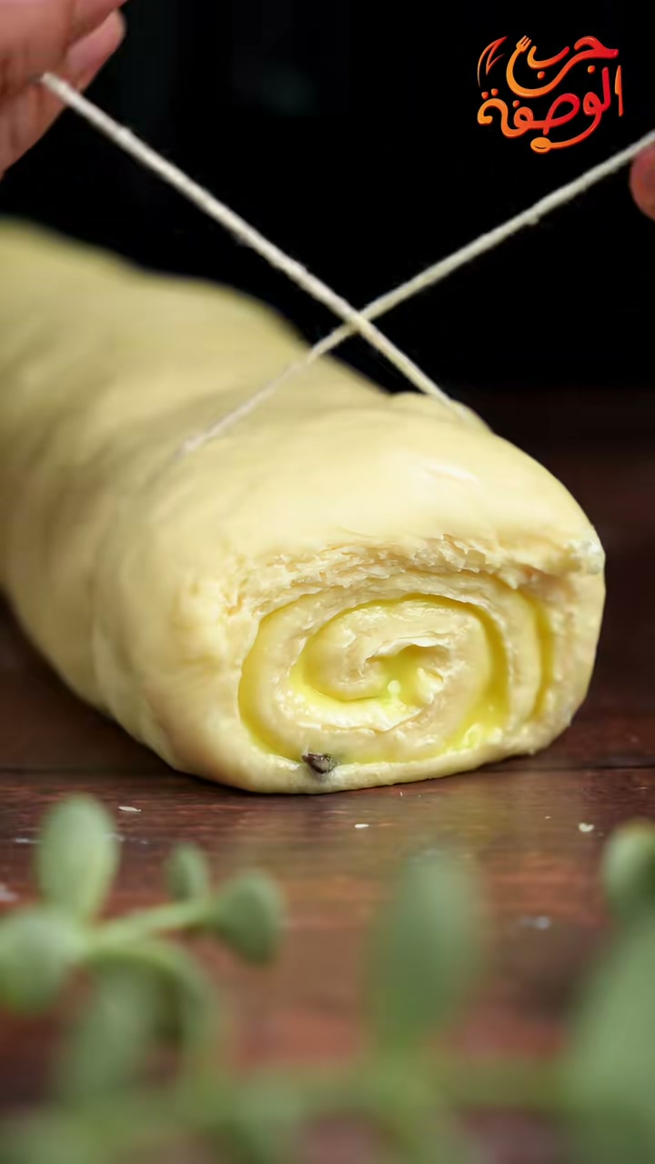 Slicing the rolled dough into swirls with a piece of thread