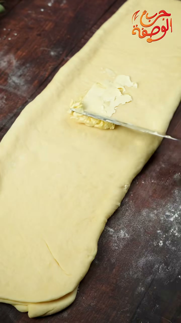 Spreading room-temperature butter over the rolled-out dough