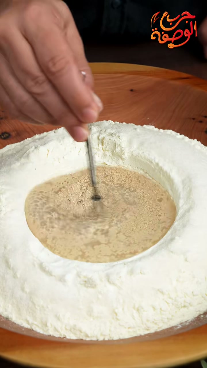 Mixing the dissolved yeast in a well in the flour